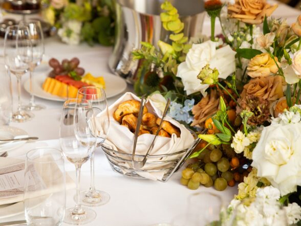 Lavishly arranged private dining table at L'Ermitage Beverly Hills featuring fresh floral centerpieces with roses and seasonal blooms, bread basket, crystal stemware, and elegant white linens