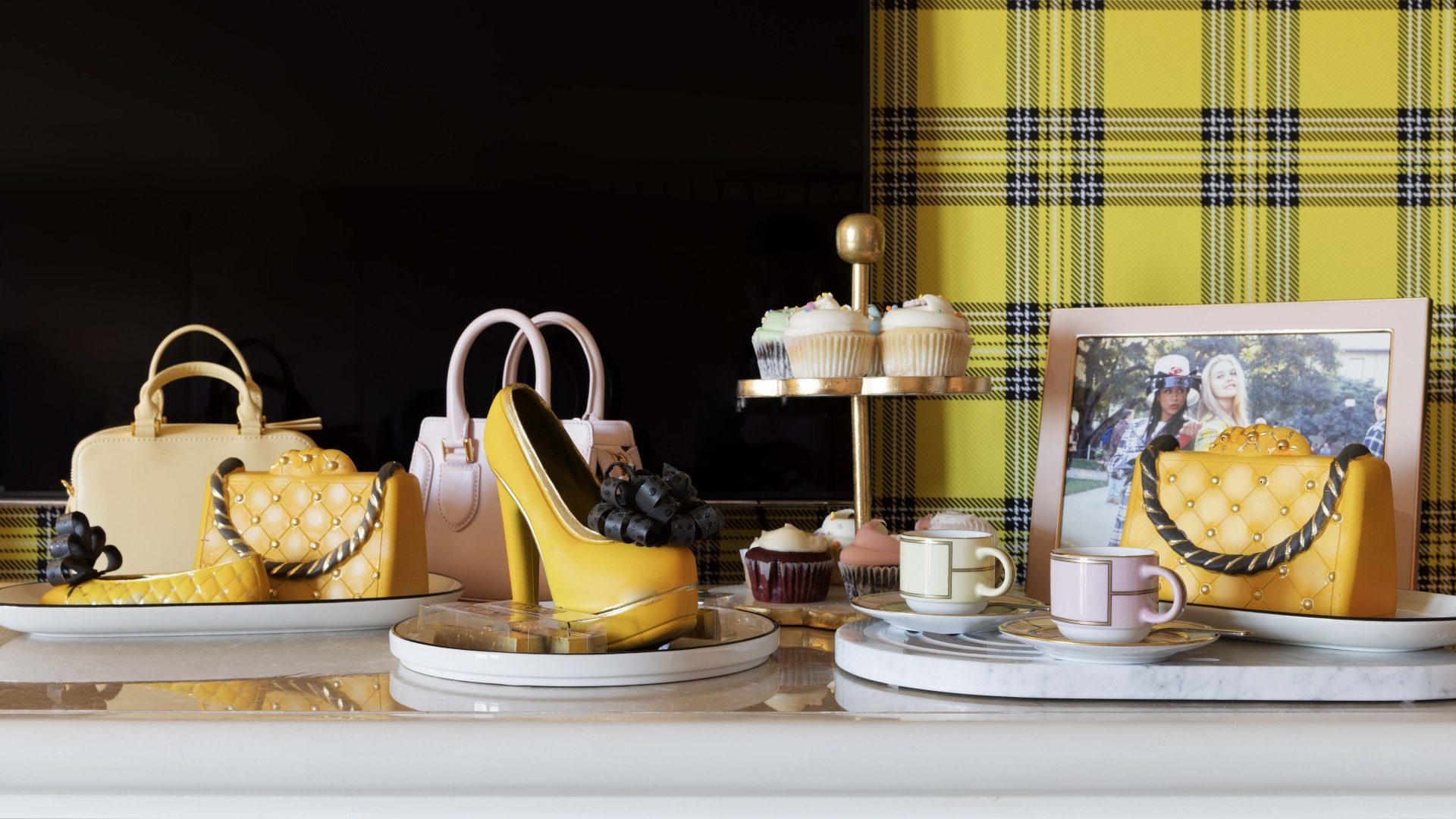 Dessert display with handbags, cupcakes, and yellow plaid backdrop