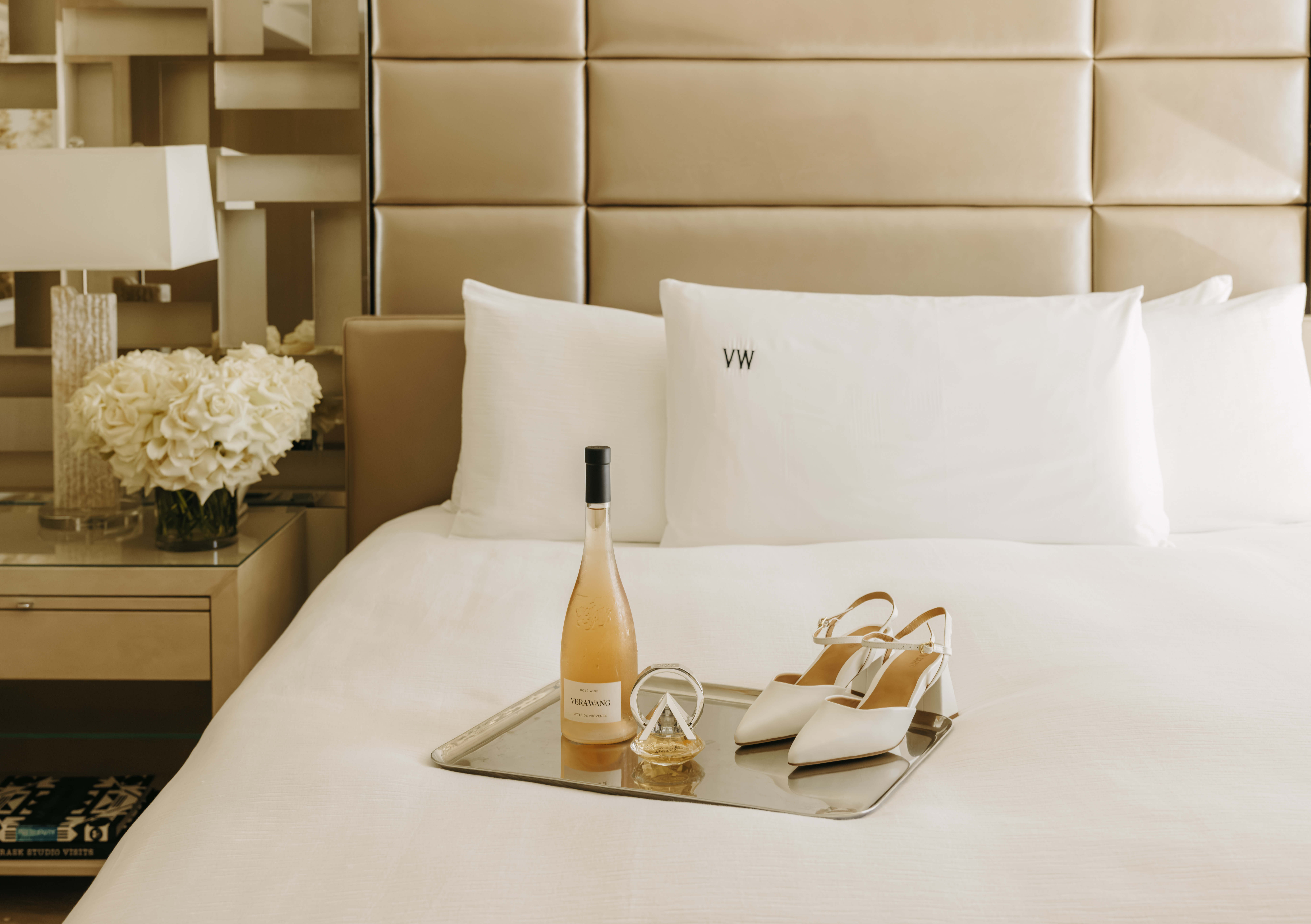 bridal suite white bed with champagne and heels placed on top